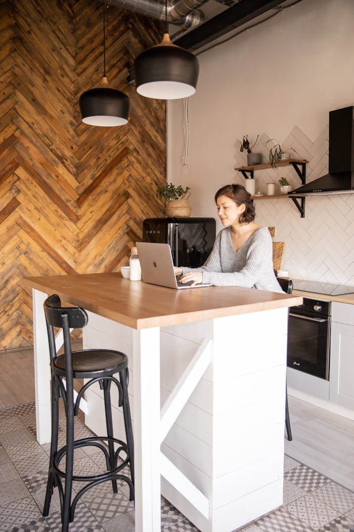 Positive young woman with laptop in modern kitchen